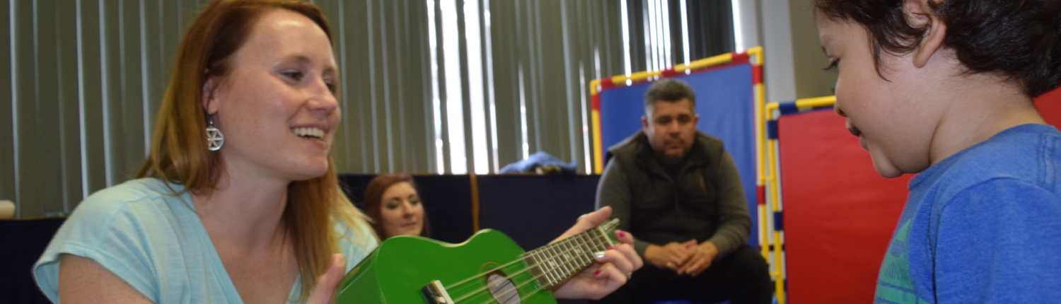 Busy Beats Music Group instructor shows guitar to boy