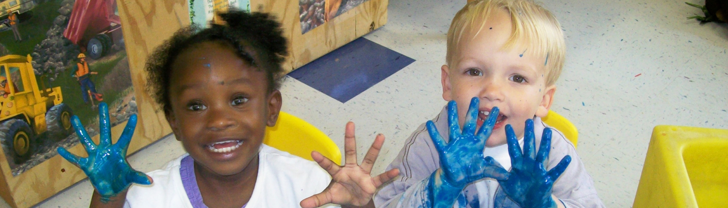 Children in early intervention smile and hold up painted hands